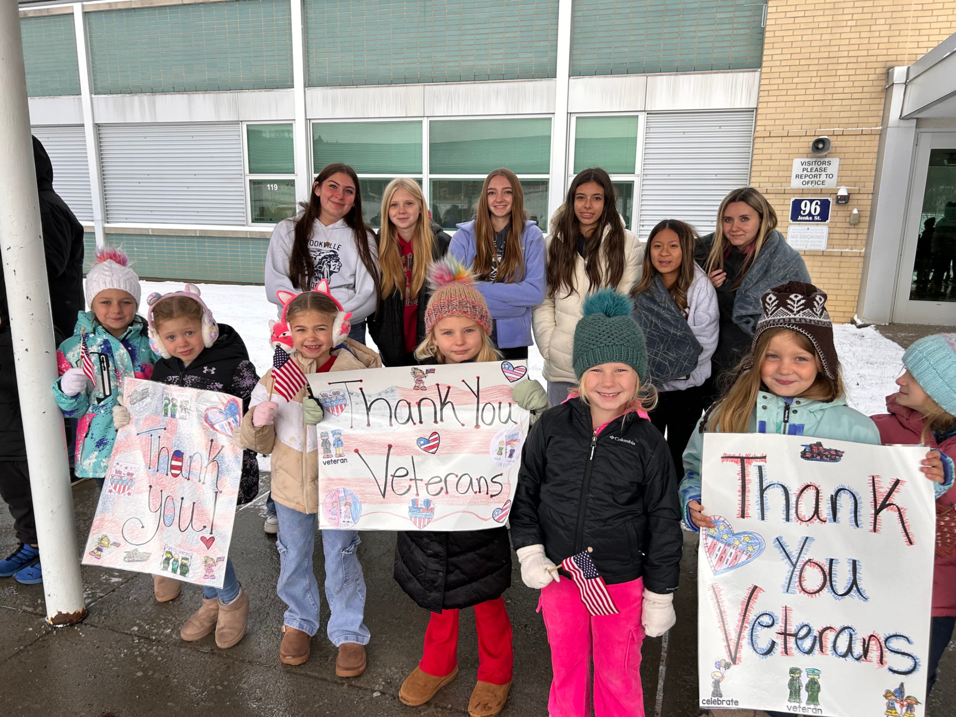 Students holding thank you signs during the veterans day parade.